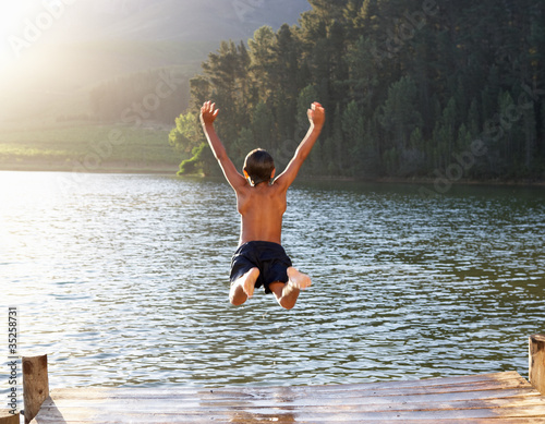 Obraz na plátne Young boy jumping into lake