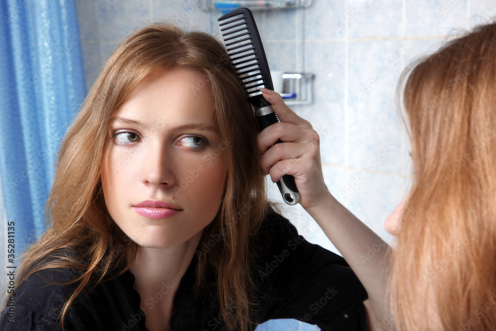 Fototapeta premium young woman in bath at front of a mirror correcting hairs