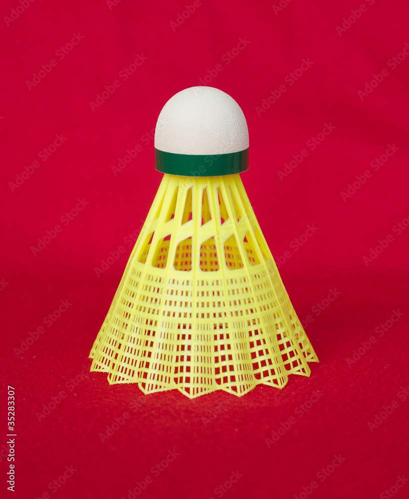 Single yellow shuttlecock isolated on red