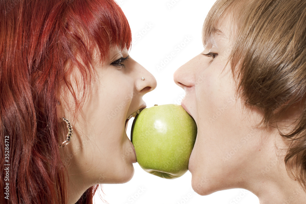 Close-up of happy couple biting a green apple from another sides Close-up of happy couple biting a green apple from another sides