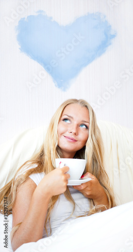 Young woman at home sipping tea or coffee from a cup and thinkin