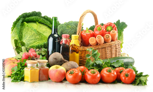 Raw vegetables and wicker basket isolated on white