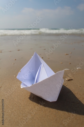 Origami paper boat on the sand at the beach