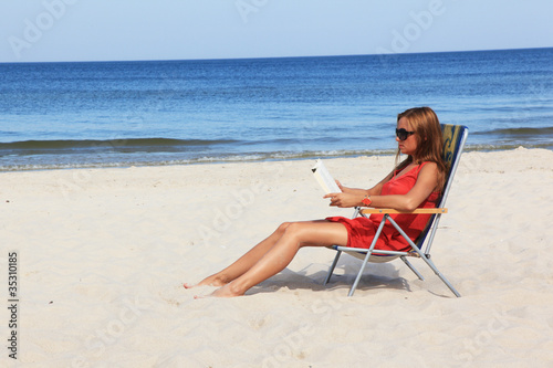 Young woman reading book on the sunny beach