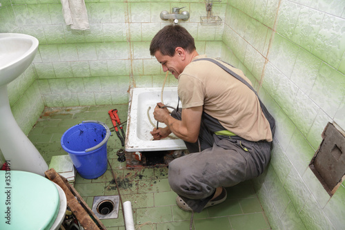 Plumber cleaning  drain in bathroom