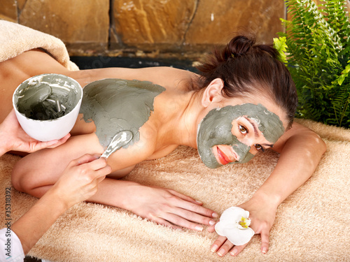 Young woman  having clay body mask. photo