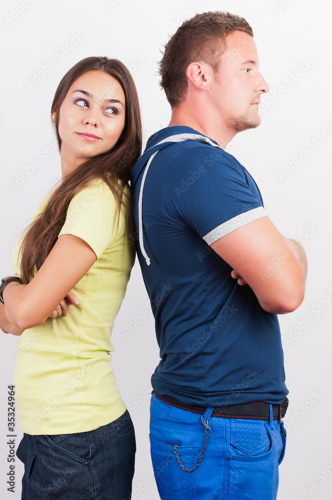 Portrait of a smiling young couple standing back to back on whit Portrait of a smiling young couple standing back to back on whit