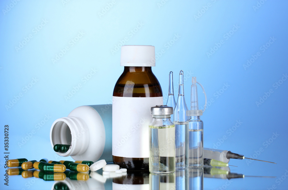 Medical bottles, ampoules and pills on blue background Medical bottles, ampoules and pills on blue background