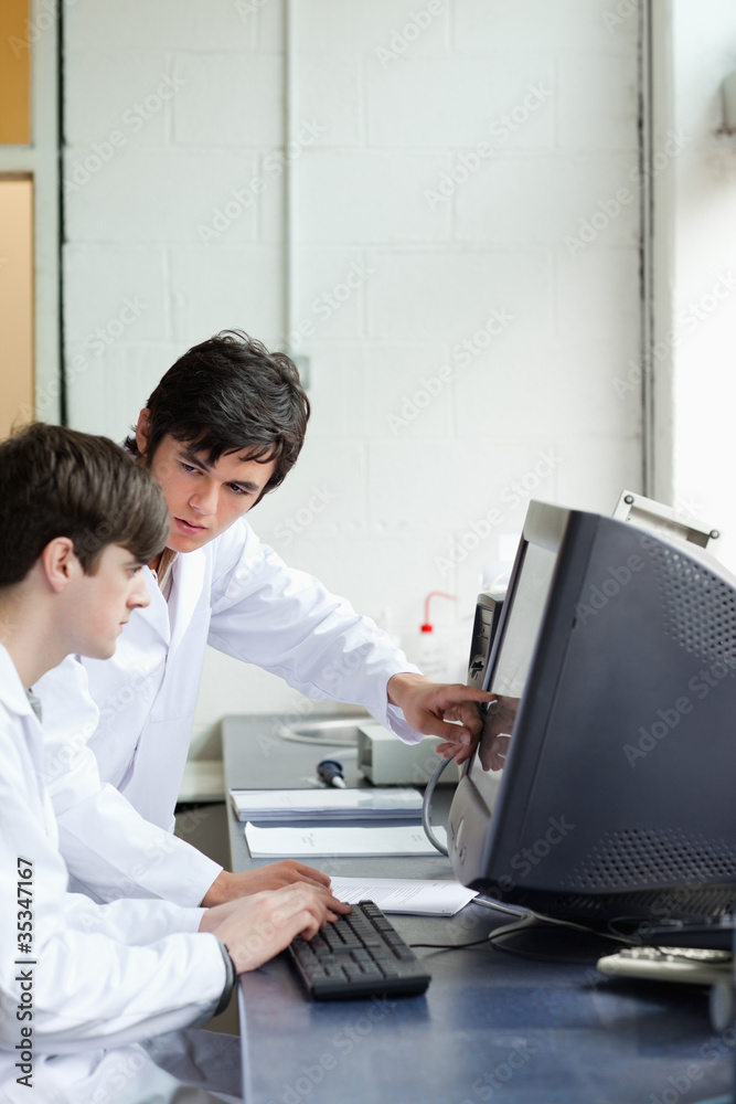 Phisician pointing at something on a monitor to his student