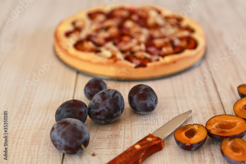 Plum pie and plums on a wooden background