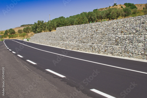 Strada asfaltata con muro di sostegno in curva