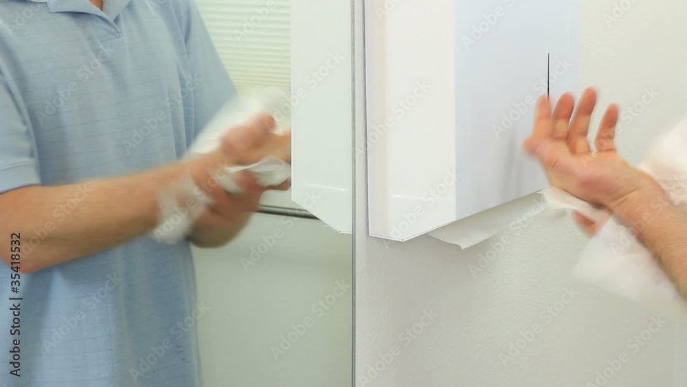 Man drying hands with paper towels in a bathroom