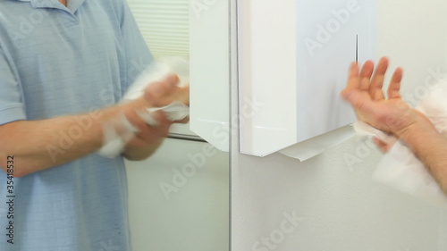 Man drying hands with paper towels in a bathroom