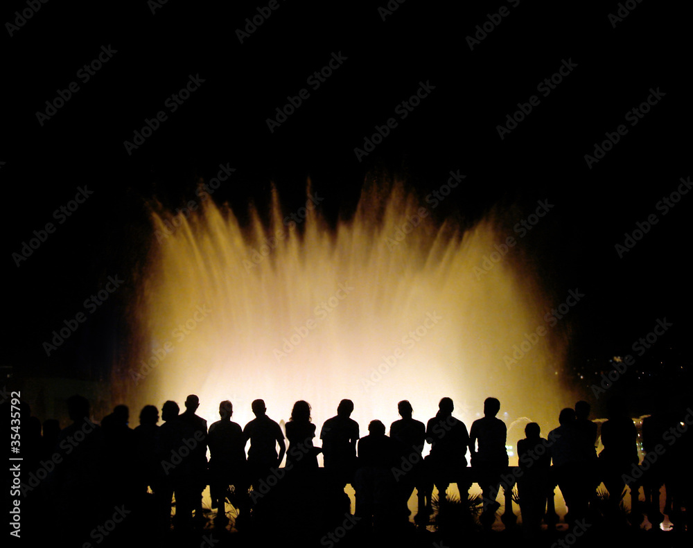 Fototapeta premium group of tourists near a colour musical fountain in barcelona, s