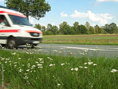 Krankenwagen fährt im Notfall schnell über Landstraße, Landschaft im Hintergrund, Niedersachsen, Deutschland