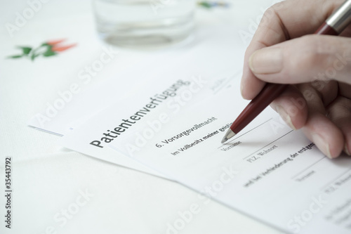 seniorenhand füllt eine Patientenverfügung aus