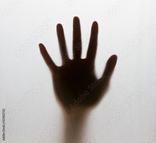 Shadow of a blurry hand behind the frosted glass