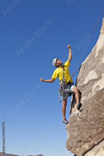 Male rock climber clings to a cliff.