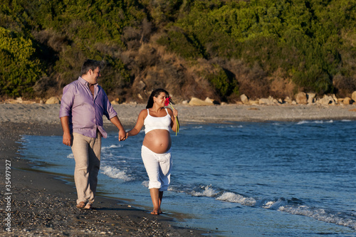 Couple expecting a baby walking on the beach