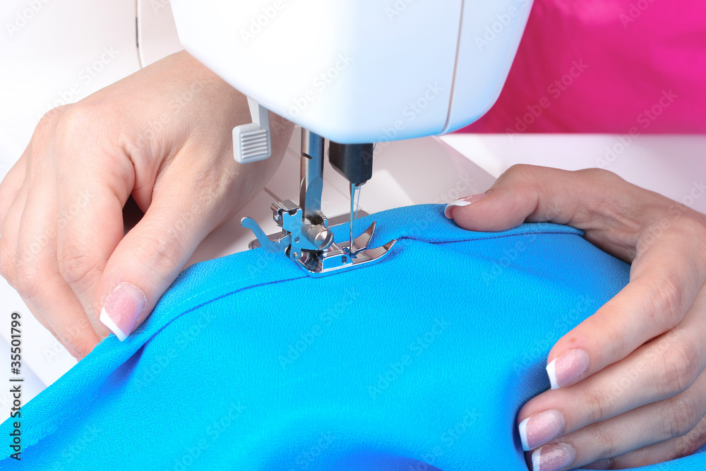 sewing machine, blue fabric and women's hands