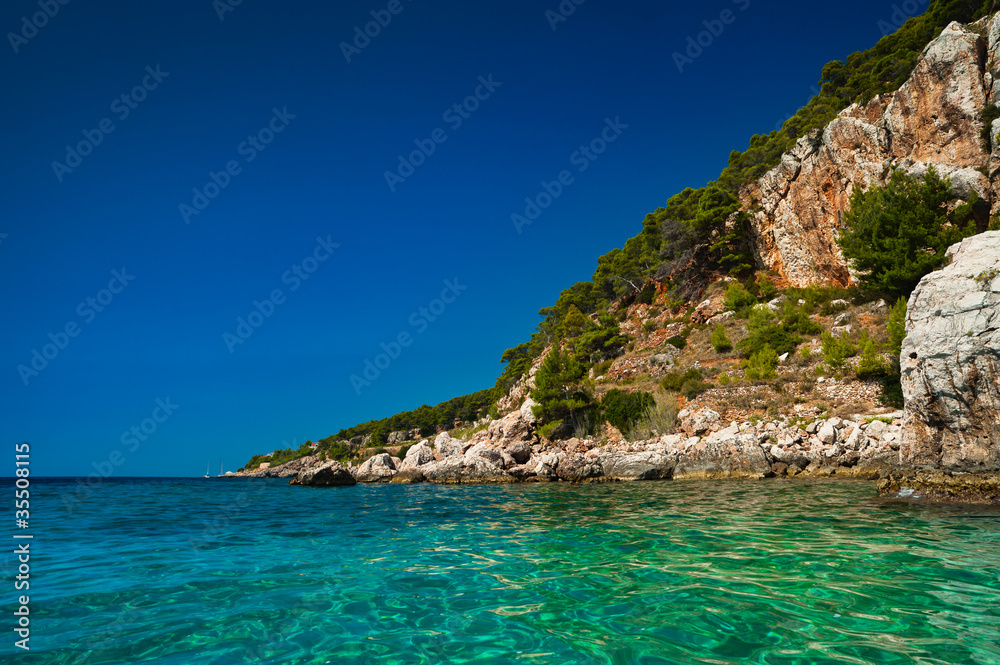 Island cliffs at turquoise sea water. Adriatic coast of Hvar
