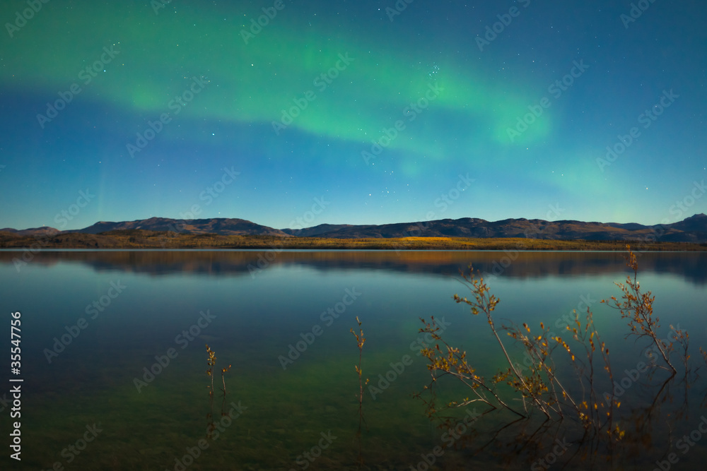 Northern lights and fall colors at calm lake