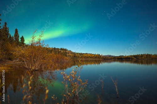 Northern lights and fall colors at calm lake photo