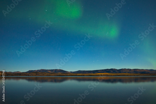 Northern lights and fall colors at calm lake © PiLensPhoto