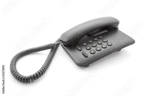 Black office telephone with soft shadow on white