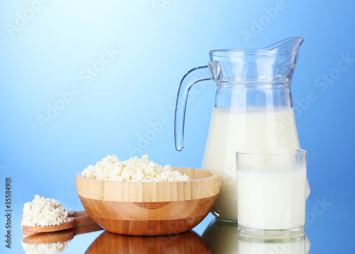 Tasty milk and cottage cheese on blue background