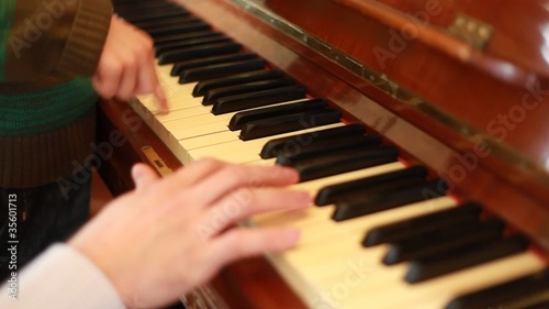 Closeup of hands of father and son playing on piano photo