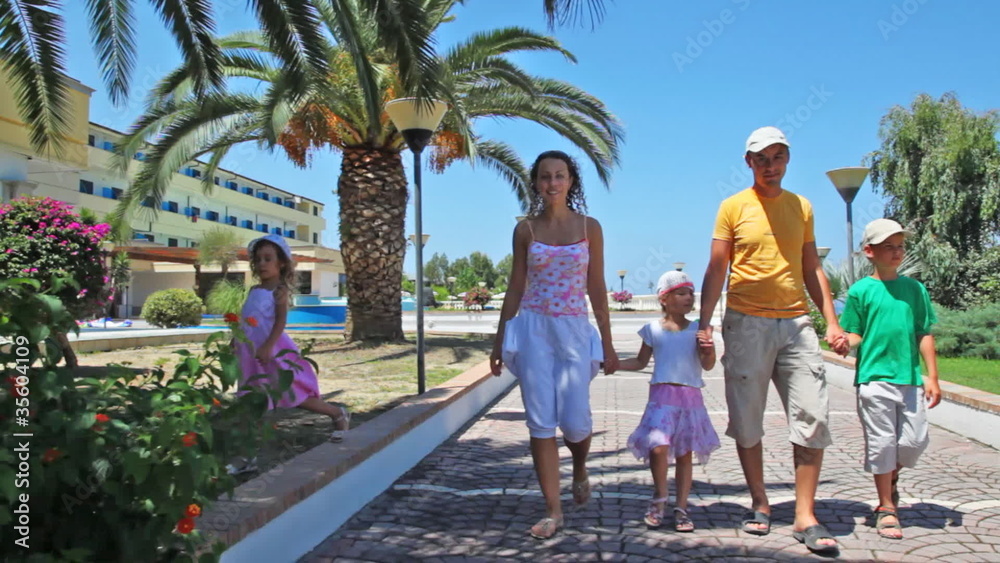 Family goes on walkway lined with palm trees and flowers Family goes on walkway lined with palm trees and flowers