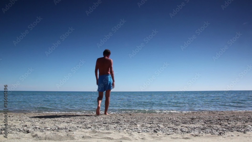 Man walk by beach sand to water then return