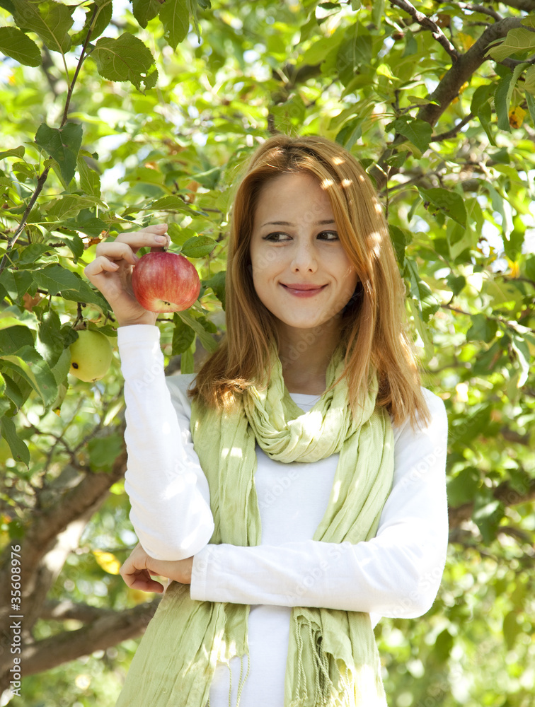 Beautiful young redhead woman standing near the apple tree. Beautiful young redhead woman standing near the apple tree.