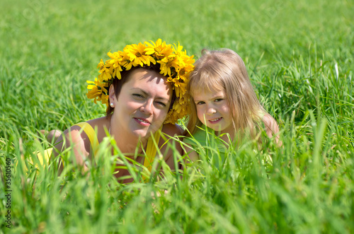 Mom and baby daughter are in the high green grass