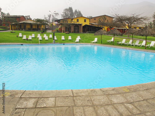 Swimming pool area of hotel with umbrella and beach chair