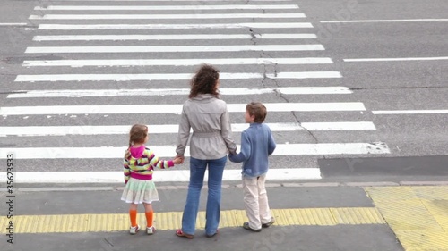 Mother and children, stand and wait to cross road photo