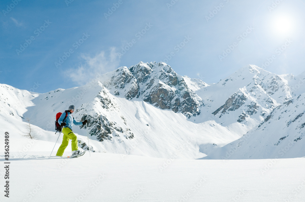 Snowshoeing - female trekking in snow racket