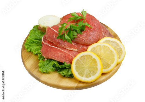 Raw beef meat with lemon and greens