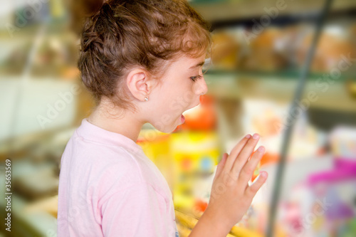 child little girl looking in food shop display © lunamarina