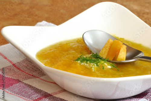 zupa z dyni w białym talerzu na serwetce