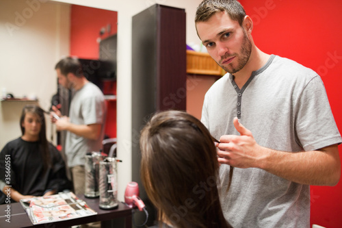 Serious male hairdresser cutting hair