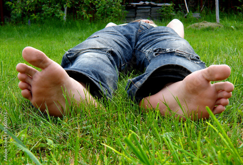 foot and a heel of the young man laying on a grass
