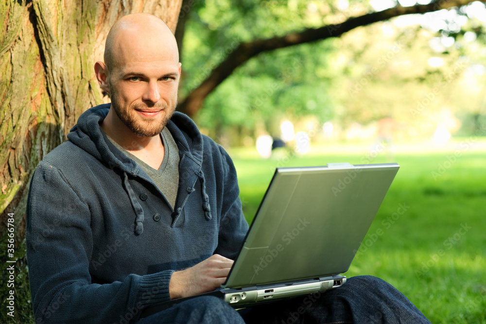Young man with notebook in park Young man with notebook in park