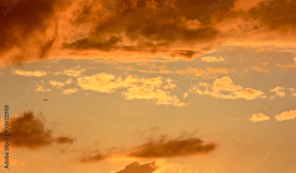 Fototapeta premium Aeroplane flying through dramatic sunset