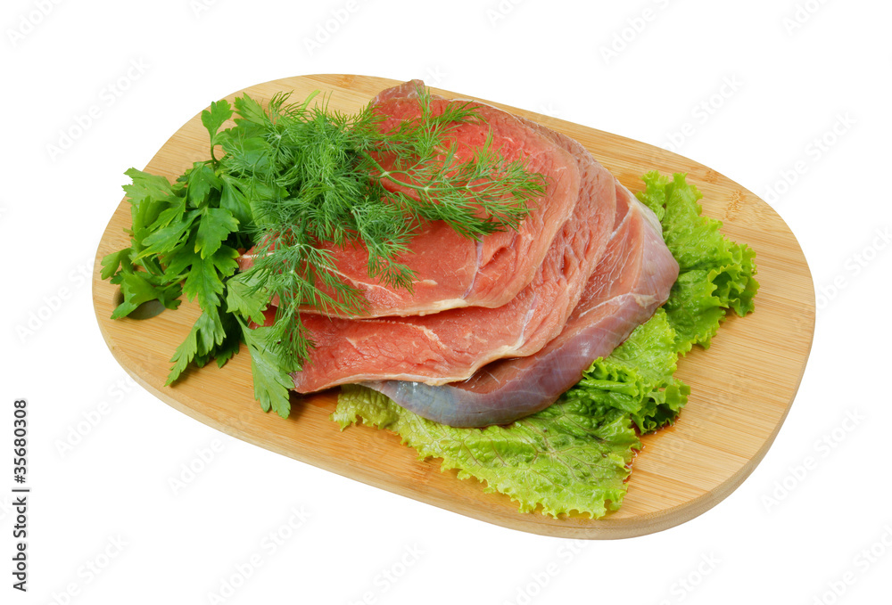 Raw beef meat with greens on cutting board Raw beef meat with greens on cutting board
