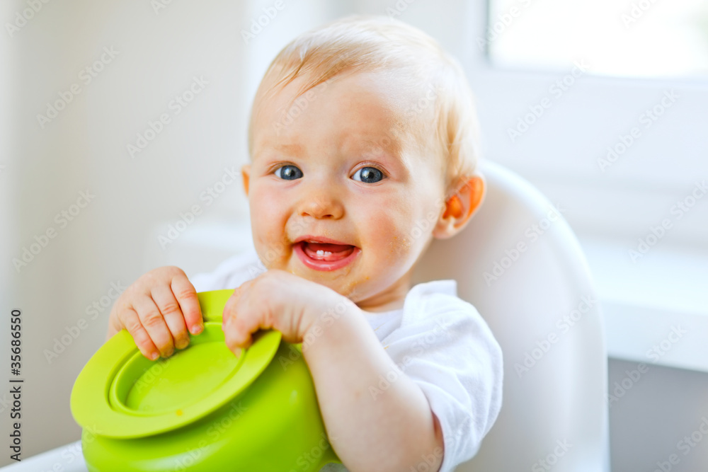 Adorable baby sitting in baby chair and playing with plate Adorable baby sitting in baby chair and playing with plate
