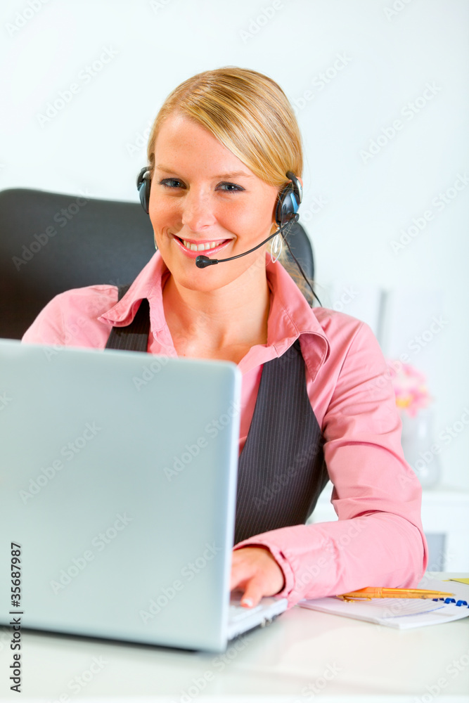 Smiling business woman with headset working on laptop Smiling business woman with headset working on laptop