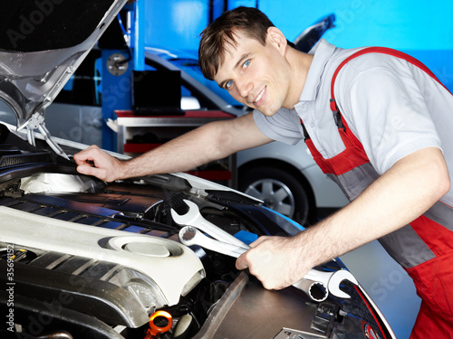 Motor mechanic is fixing the engine of a car carfully photo