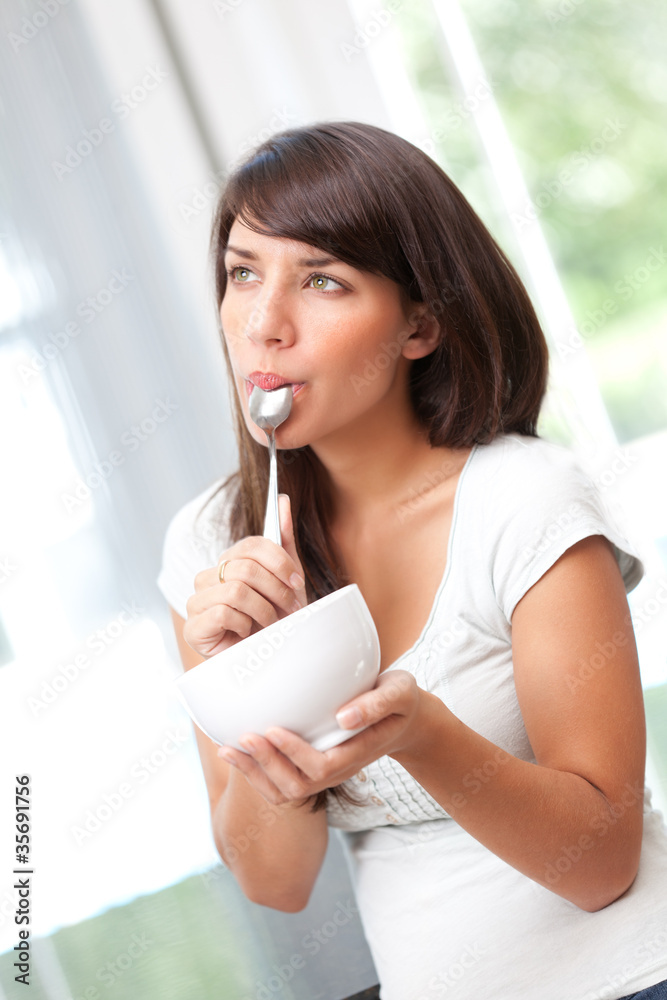 Woman eating from bowl and thinking Woman eating from bowl and thinking